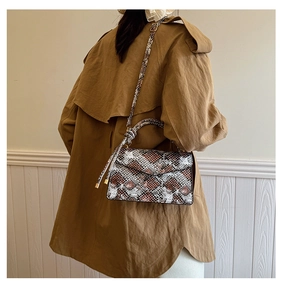 Fashionable snakeskin crossbody bag with brown and black texture patterns on a model