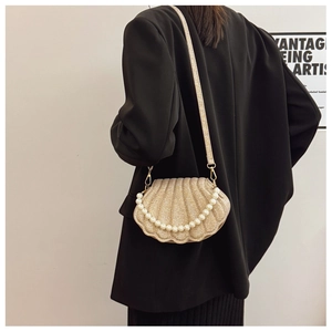 Detail of a shell-shaped gold evening bag with glitter texture and pearl chain handle