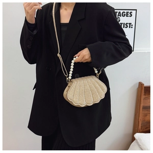 Detailed view of champagne gold shell-shaped bag with pearl handle and woven strap