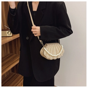Detail of shell-shaped crossbody bag with champagne glitter finish and pearl handle