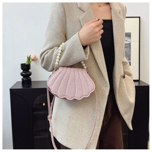 Model wearing a pink glitter shell handbag with pearl handle and shoulder strap