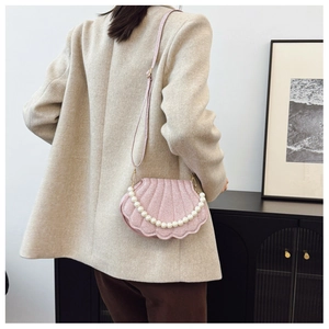 Detail of pink shell crossbody bag featuring elegant pearl chain and shimmery texture