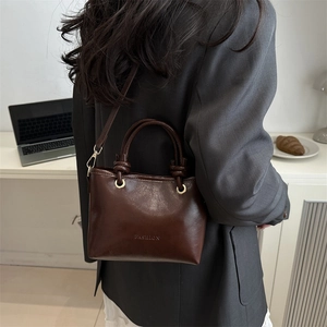 Fashion dark brown leather bucket bag with top knot handles and gold hardware crossbody strap