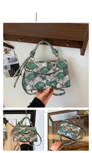 Close-up of green snake pattern faux leather handbag with knotted handle and flap