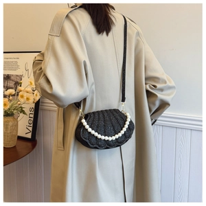 Detail of black glitter shell bag with large white pearls on a trench coat model