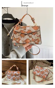 Detailed view of the orange snakeskin pattern handbag with knotted handle and metal rings