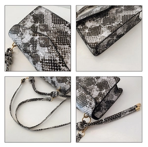Detail view of grey snakeskin pattern faux leather handbag with gold hardware