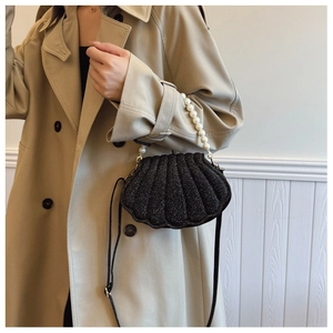 Close-up of shell-shaped sequin handbag with pearl handle and elegant pleat texture