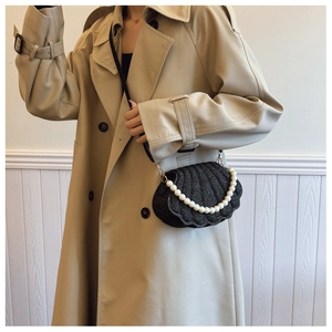Detail of a black sequined shell bag featuring a pearl handle and slim shoulder strap