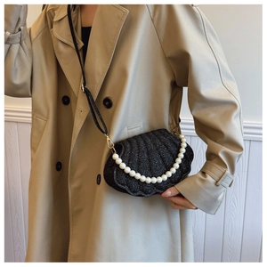Detail shot of black shell shaped handbag with glitter texture and pearl handle
