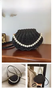 Close-up of black shell-shaped evening bag with glitter rhinestones and pearl handle