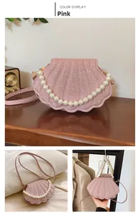 Detailed view of pink shell-shaped pearl handbag with shiny fabric texture and strap