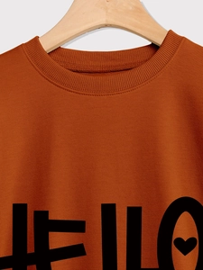 Detalle del cuello acanalado y estampado HELLO negro en una sudadera casual caramelo