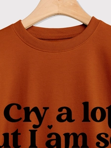 Detail of ribbed crew neck and black heart text print on orange cotton sweatshirt