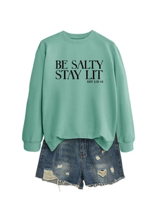 Detail of mint green sweatshirt with BE SALTY STAY LIT print and frayed denim shorts