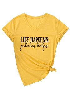 Detail of V-neck mustard yellow T-shirt with 'life happens pilates helps' print and side knot