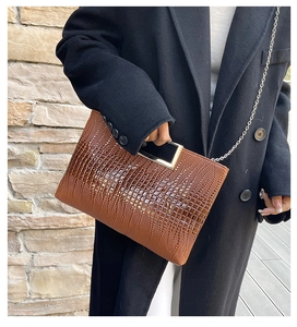 Close-up of brown croc-effect bag featuring gold rectangular handle and chain strap