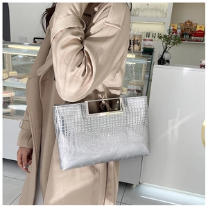 Detail of silver crocodile pattern handbag with metal handle and chain strap