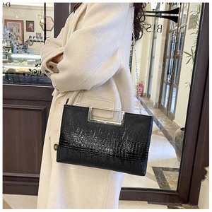 Detail of black crocodile texture bag with silver hollow metal handle and chain strap