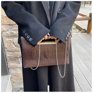 Brown crocodile pattern clutch bag featuring gold frame closure and silver chain strap
