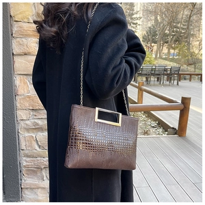 Detail of dark brown crocodile embossed leather with gold handle and chain strap