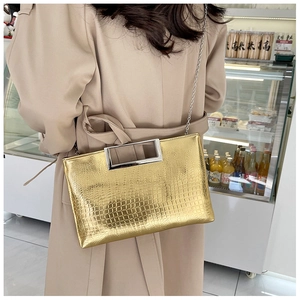 Detailed view of crocodile embossed pattern on gold crossbody bag with silver handle