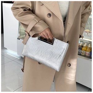 Close-up of silver crocodile embossed leather bag with metal handle and chain strap
