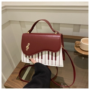 Détails du motif de touches de piano et de la clé de sol dorée sur le sac à bandoulière rouge