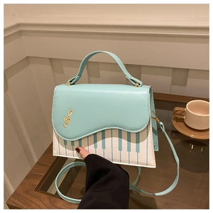 Détail du sac bleu en cuir avec motif de touches de piano et clé de sol dorée