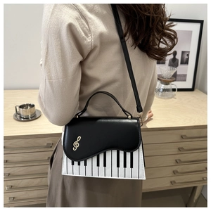 Détail du motif de touches de piano et fermoir clé de sol doré sur le sac à main
