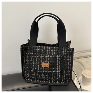 Close-up of thickened tweed lunch bag featuring black and gold texture and leather label