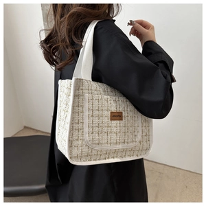 Close-up of checkered tweed bucket bag with beige weave and branded leather patch detail