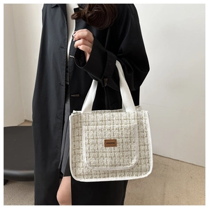 Detail of tweed lunch tote bag with woven texture and a leather logo on front pocket