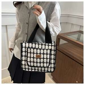 Detail of tweed checkered tote bag featuring a leather JINGPIN logo and fabric handles
