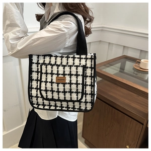 Close-up of black and white checkered tote bag with leather tag in a home setting