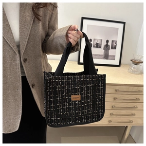 Detail of woven tweed tote bag with black and gold plaid texture and JINGPIN leather label