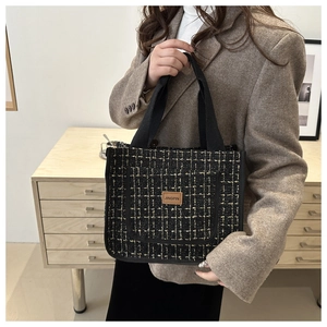 Detail view of tweed tote bag with Jingpin leather patch and black strap on mannequin