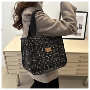 Detail of tweed lunch bag showing the JINGPIN leather label and woven fabric texture
