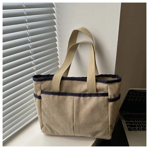 Detailed corduroy tote bag showing side pocket texture and contrast blue trim finish