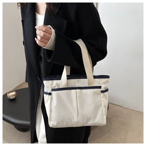 Detail of corduroy tote bag with vertical texture, blue trim, and multiple front pockets