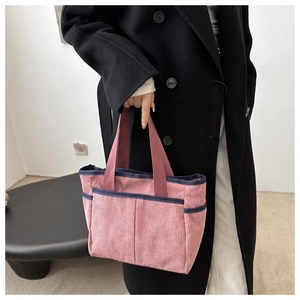 Detail of pink corduroy tote bag with blue handles featuring a practical outer pocket