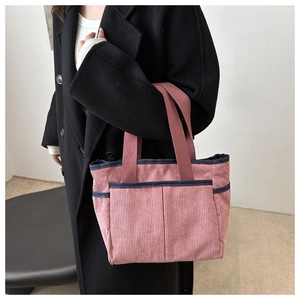 Pink corduroy tote bag detail showing dual front pockets and navy blue trim accents