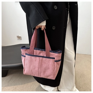 Detail of pink corduroy tote bag featuring blue trim and functional front pockets