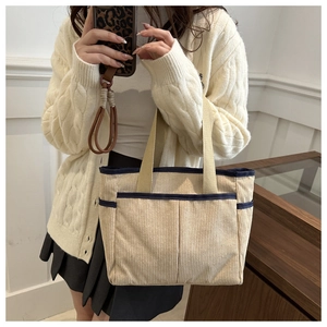 Detail of beige corduroy tote bag with navy blue trim and textured vertical stripes