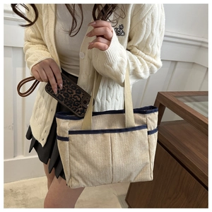 Detail of corduroy tote bag with navy contrast piping and front exterior pockets
