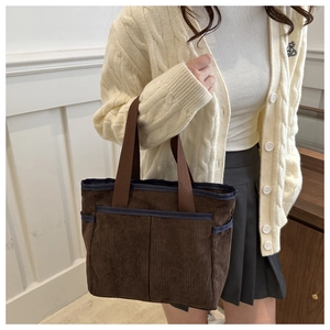 Detail of dark brown corduroy tote bag with blue trim pockets and sturdy woven handles