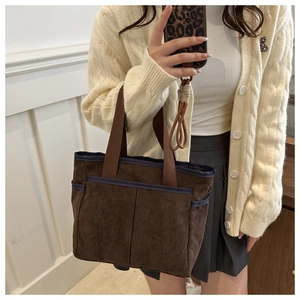 Detail of dark brown corduroy tote bag with two front pockets and blue fabric trim