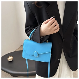 Detail der hellblauen Kunstleder-Handtasche mit goldener Metallschnalle und feiner Textur