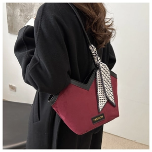 Detail of burgundy tote bag with V-shaped cut and decorative black and white checkered scarf