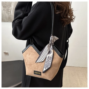 Detail of tan suede tote bag featuring black leather trim and decorative silk scarf
